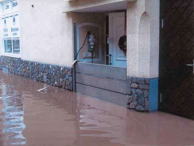 Haus im Hochwasser; die Abschottung am Eingang hält das Wasser draußen.
