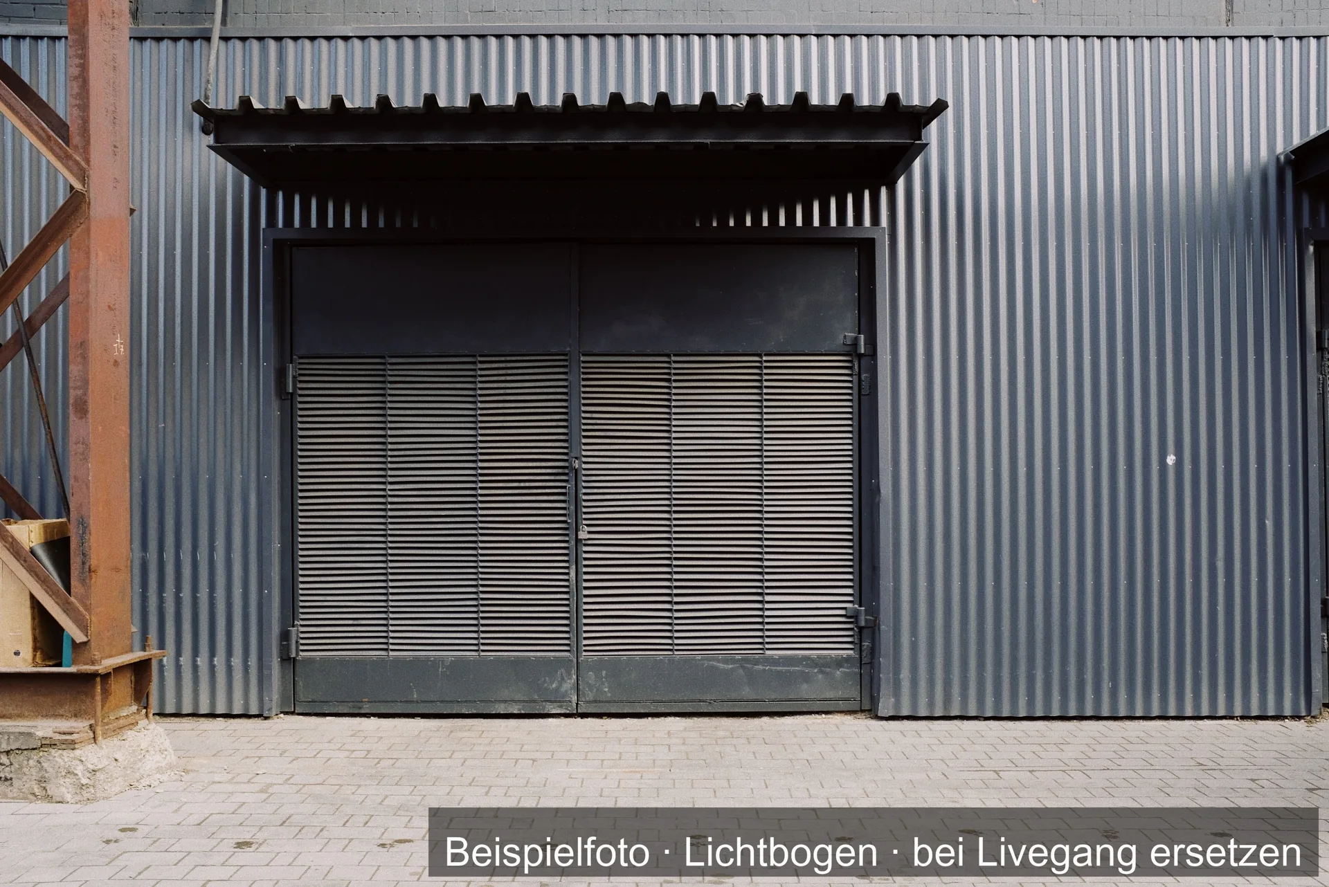 Zweiflügelige Stahltür unter einem Vordach in einer Halle mit Trapezblechfassade.